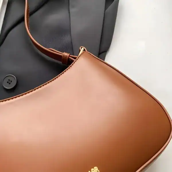 Svart halvmånsväska i läder, elegant axelväska med guldfärgad detalj och brunt handtag.