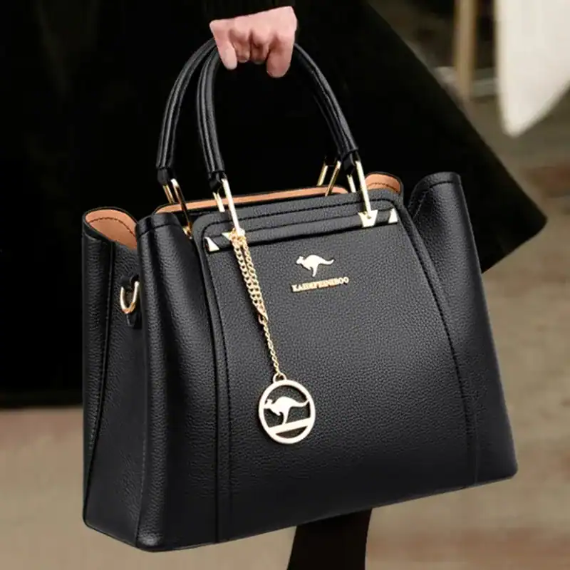 Svart handväska med hänge, läder, elegant, axelväska, damväska, handtag, metalldetalj.