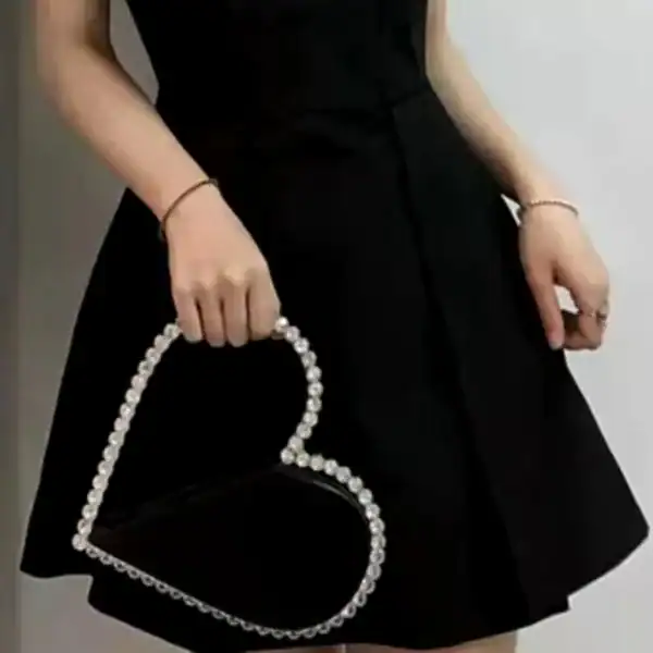 Svart hjärtformad clutch med strass och silverfärgad handtag.