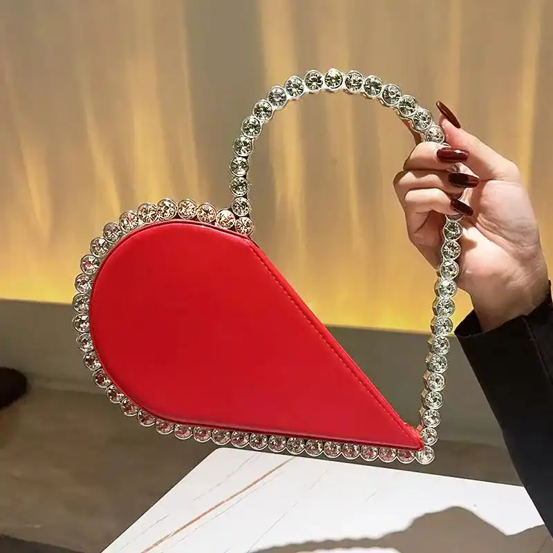 Röd hjärtformad clutch med strass och handtag, perfekt för festliga tillfällen.