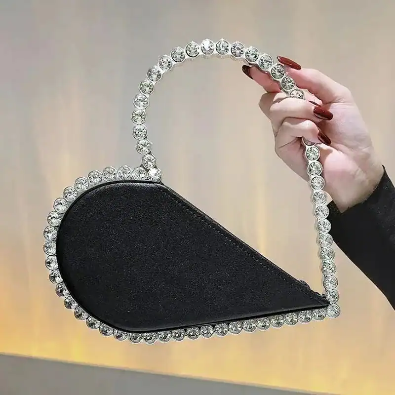 Svart hjärtformad clutch med strass och silverfärgad handtag.