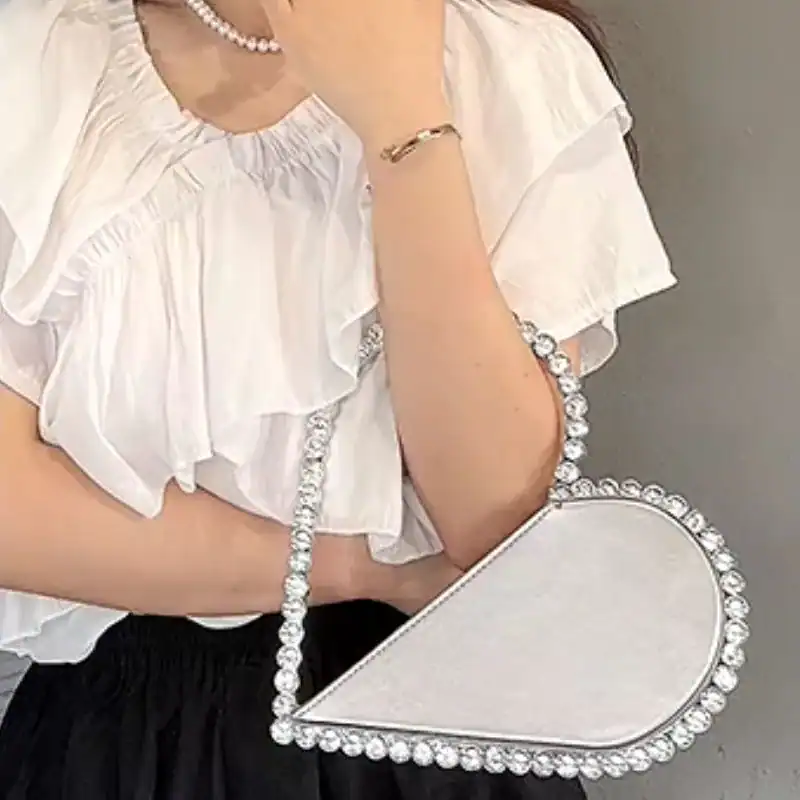 Svart hjärtformad clutch med strass och silverfärgad handtag.