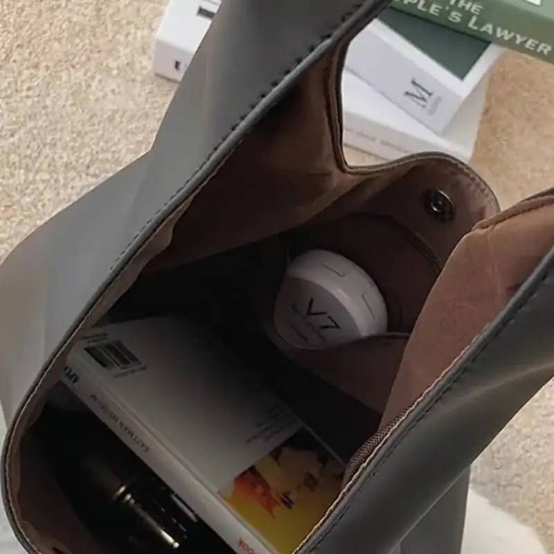 Svart hobo väska med innehåll, böcker och kosmetik, praktisk och stilren axelväska.