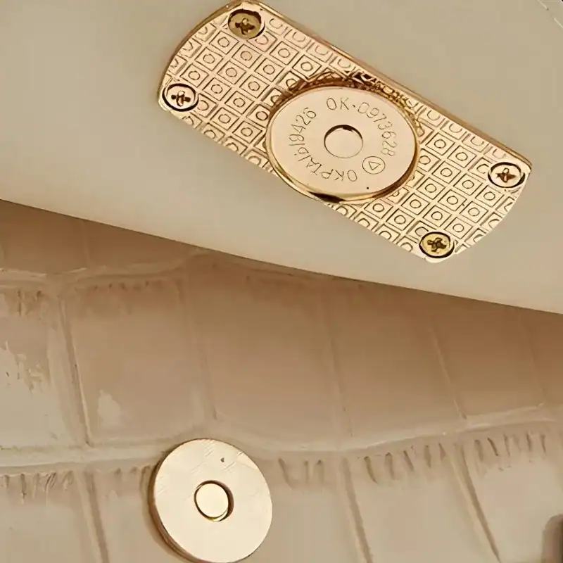 Svart krokodilmönstrat väskset med guldaktig metallplåt och rund knapp.