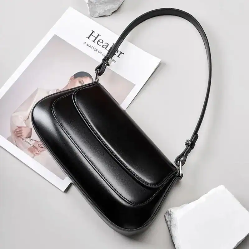 Svart lackväska med axelrem, elegant och minimalistisk design.