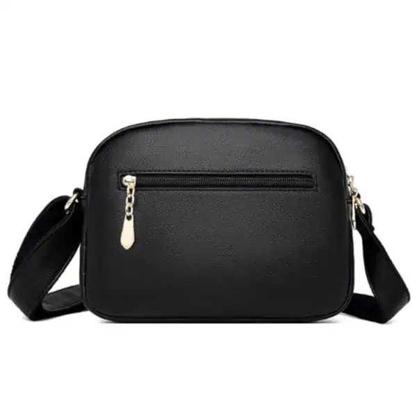 Svart liten crossbody väska med guld dragkedja och axelrem.
