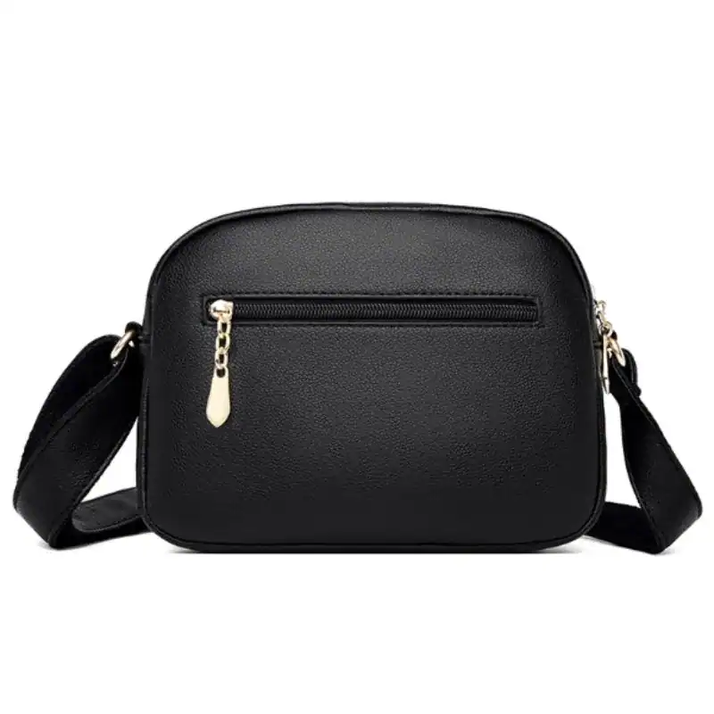 Svart liten crossbody väska med guld dragkedja och axelrem.