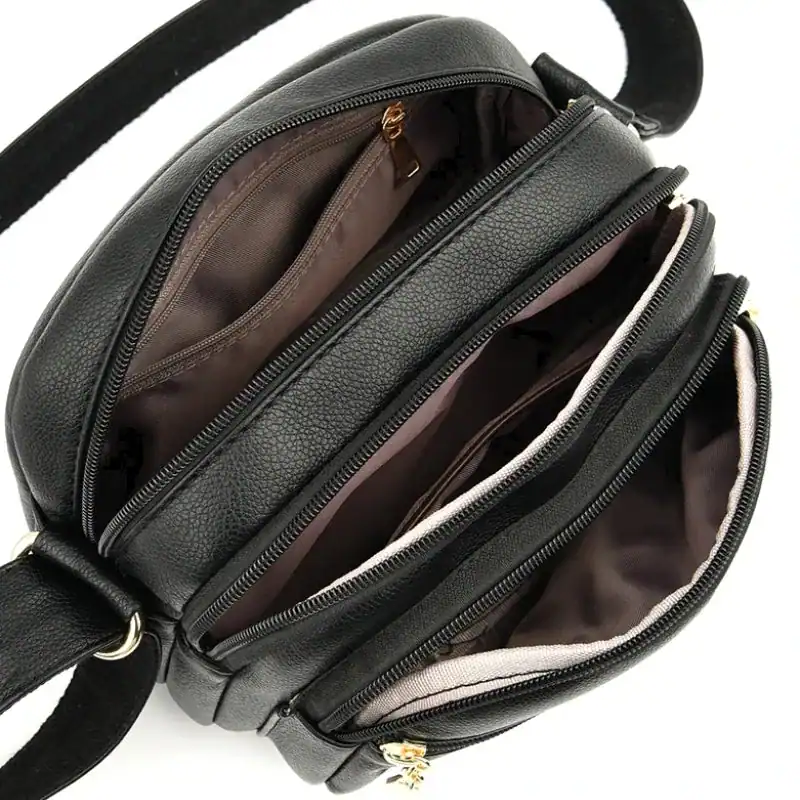 Svart liten crossbody väska med flera inre fack och dragkedja.