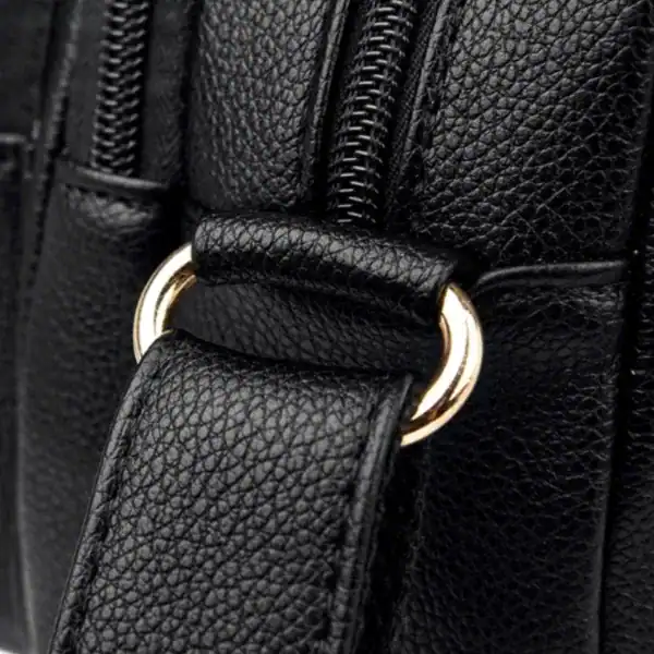 Svart liten crossbody väska med guld detaljer och texturerad läder.