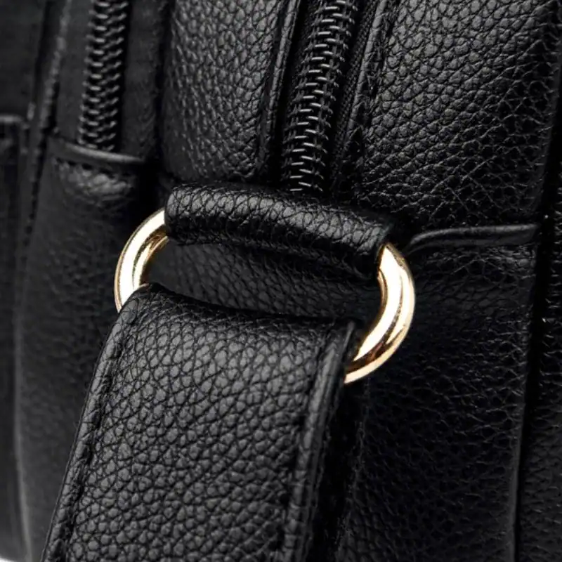 Svart liten crossbody väska med guld detaljer och texturerad läder.