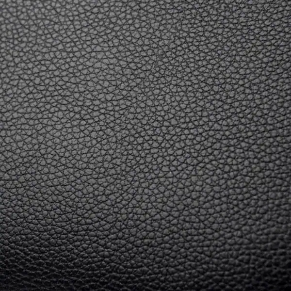 Svart liten crossbody väska i texturerat läder, detalj på ytan.