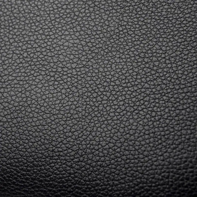 Svart liten crossbody väska i texturerat läder, detalj på ytan.