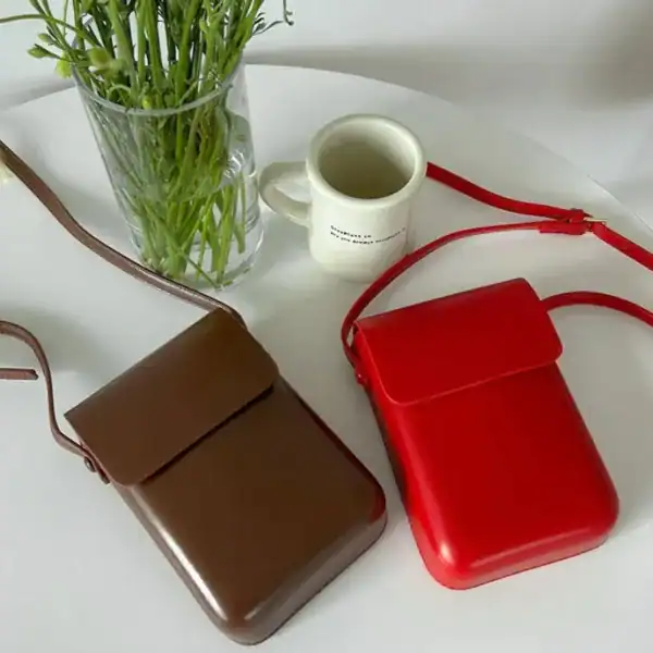 Svart mobilväska i läder, minimalistisk design med axelrem, perfekt för vardag och städ.