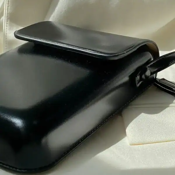 Svart mobilväska i läder med handtag, minimalistisk design för daglig användning.
