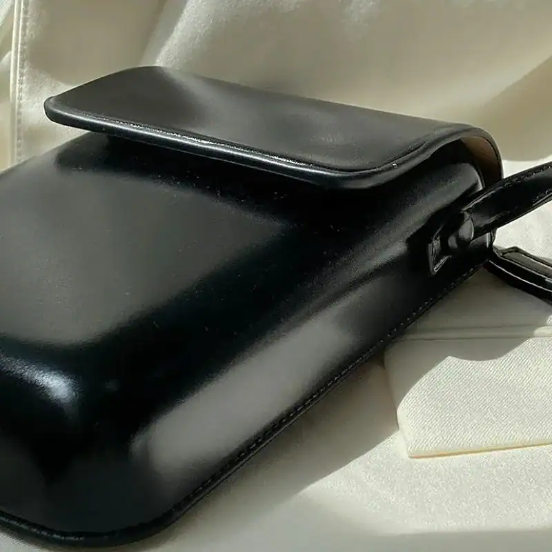 Svart mobilväska i läder med handtag, minimalistisk design för daglig användning.