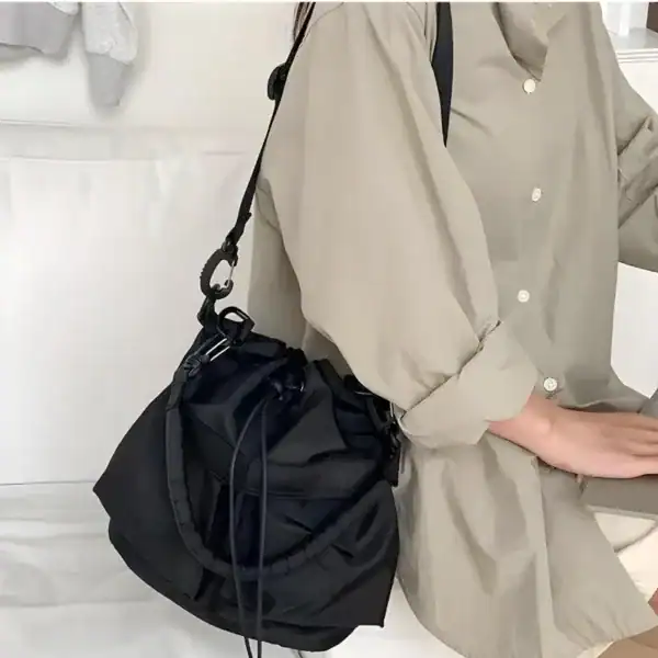 Svart nylon hinkväska med dragkedja, bära över axeln eller i handen.