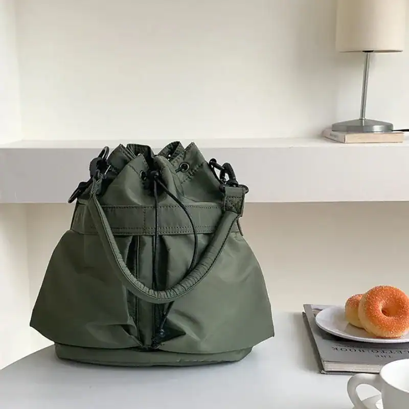 Svart nylon hinkväska med dragkedja och handtag, stilren axelväska för vardag.