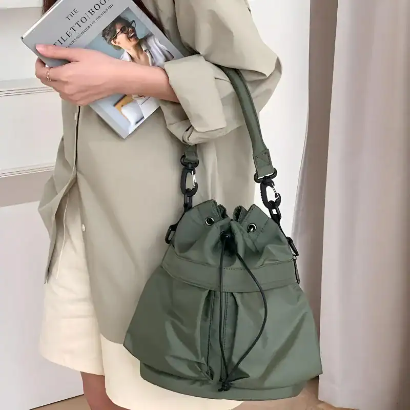 Svart nylon hinkväska med dragkedja, trendig axelväska för vardag och städ.