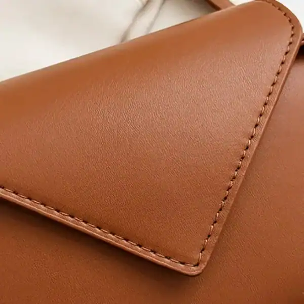 Svart oval axelremsväska i läder med exakt nässad kant och elegant design.