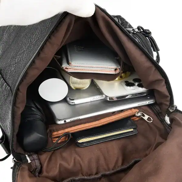 Svart ryggsäck med nitar, innehåll: mobil, tablet, plånbok och tillbehör.