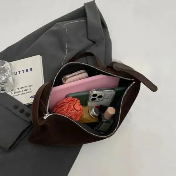 Svart sammetsclutch med innehåll, mobil och accessoarer.