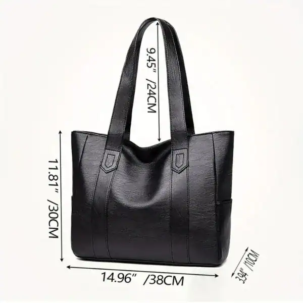 Svart tote bag med mått, läderliknande material och praktisk design.