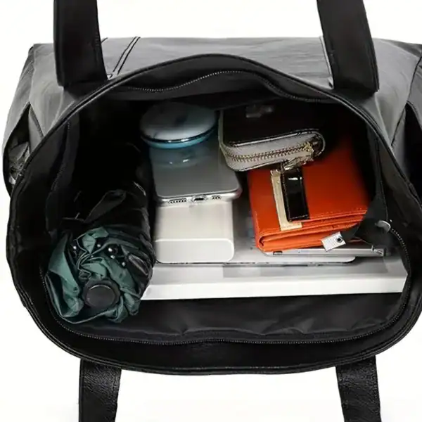 Svart tote bag med innehåll: laptop, paraply, plånbok och mobil.