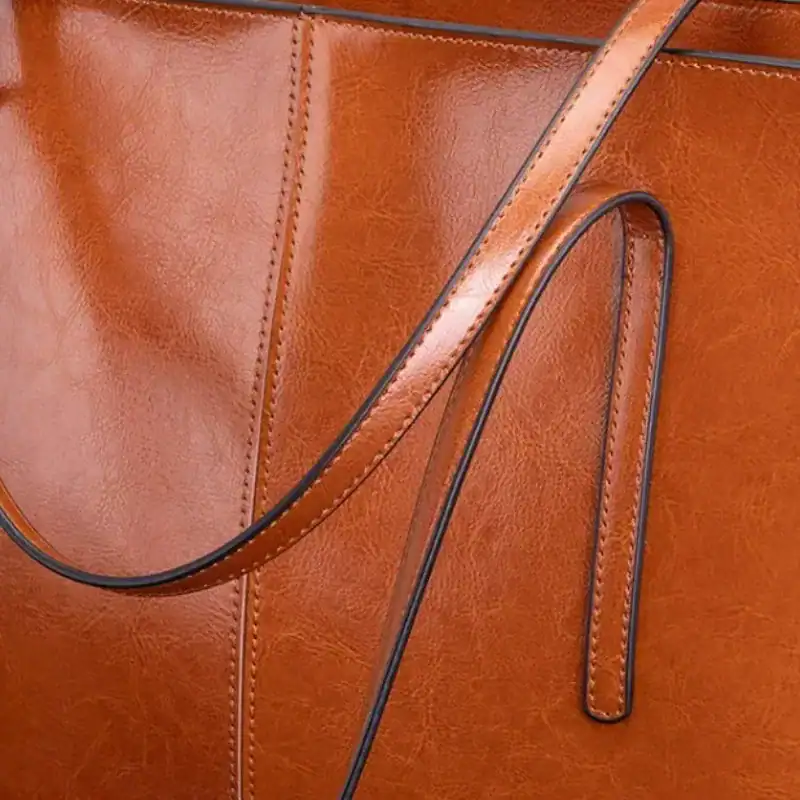 Svart tote shoppingväska i läder, närbild på handtag och sömnad.
