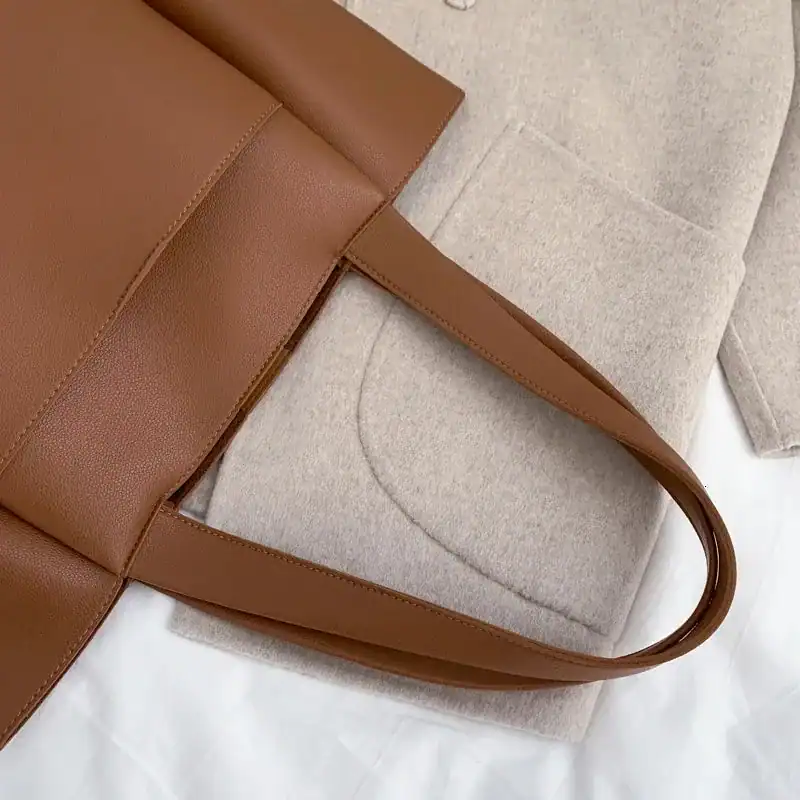 Svart tygshoppingväska med brunt handtag, stilren och modern design.
