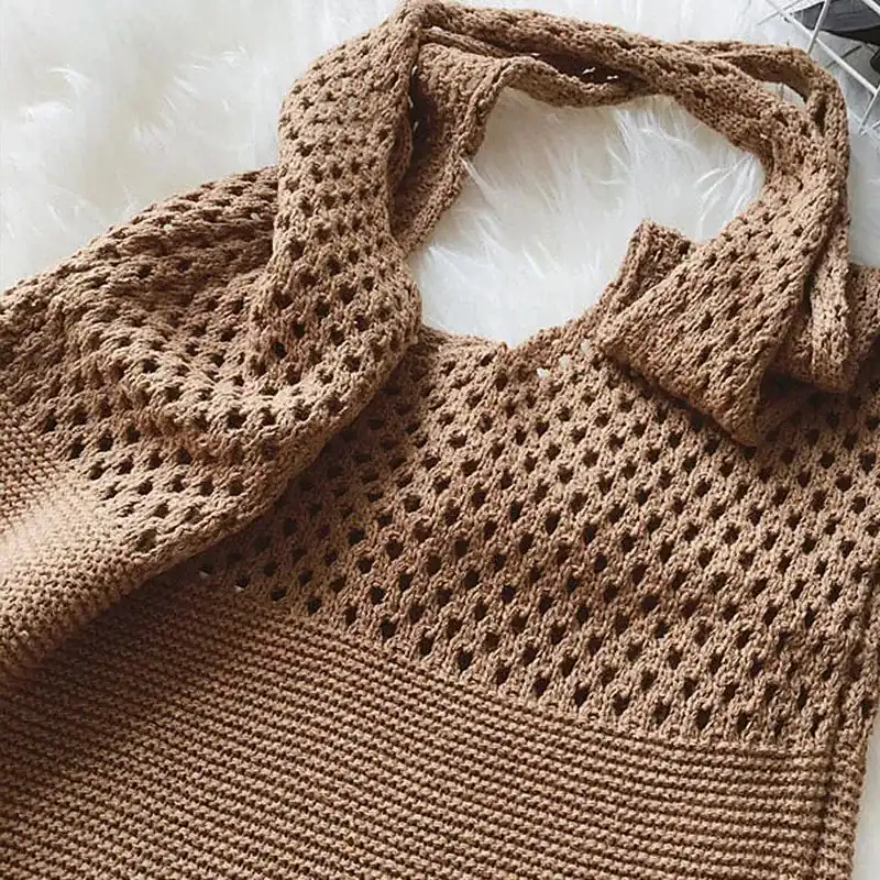 Svart tygväska triangel, handstickad axelväska i beige med öppen struktur och lång axelrem.