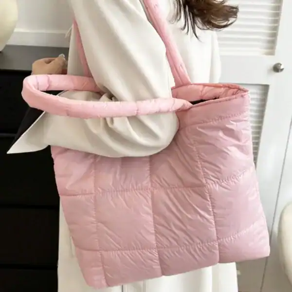 Svart vadderad shoppingväska med rosa handtag och vadderad design.