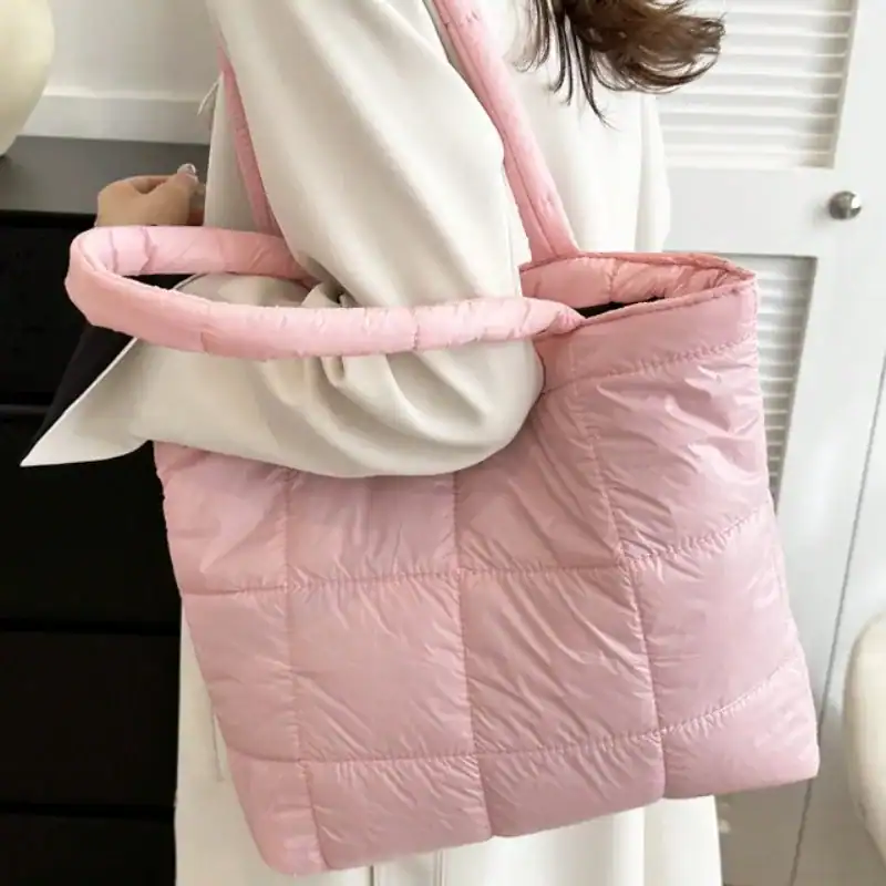 Svart vadderad shoppingväska med rosa handtag och vadderad design.