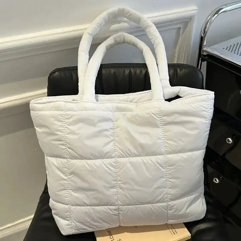 Svart vadderad shoppingväska med tjocka handtag och pufferdesign.