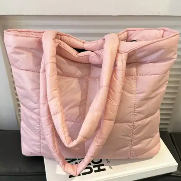 Svart vadderad shoppingväska med långt handtag och pufferdesign.