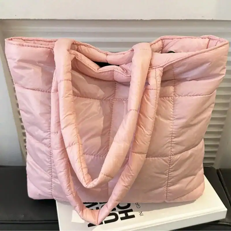 Svart vadderad shoppingväska med långt handtag och pufferdesign.