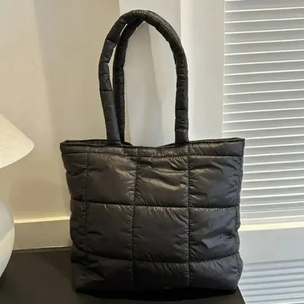 Svart vadderad shoppingväska med pufferdesign och höga handtag.