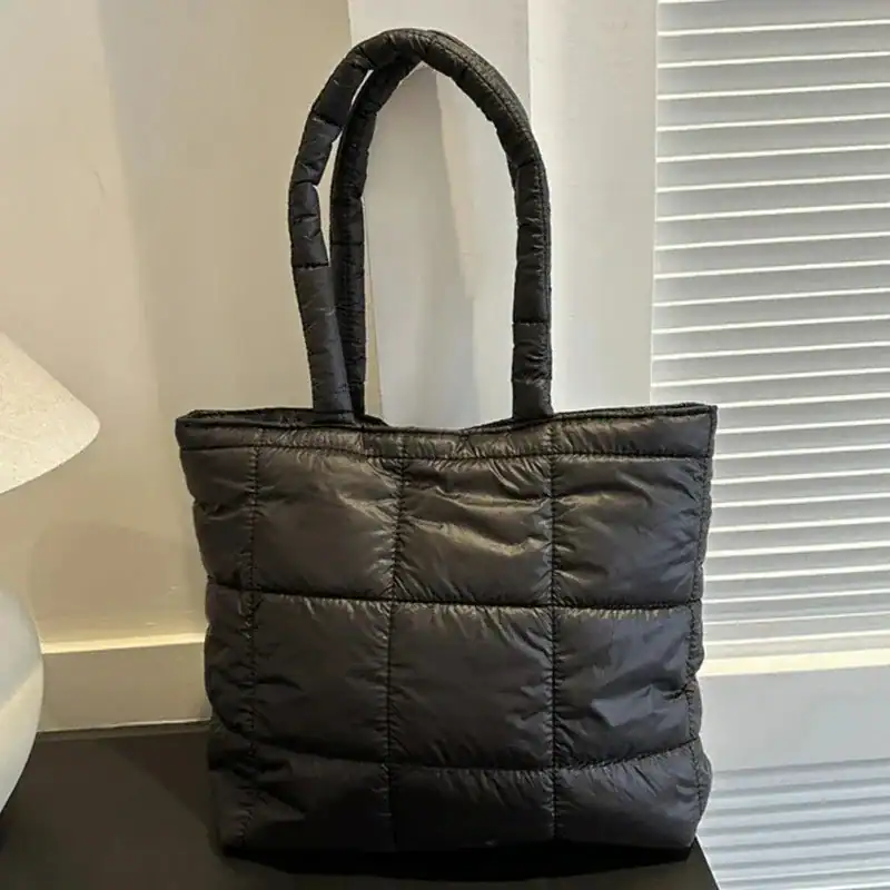 Svart vadderad shoppingväska med pufferdesign och höga handtag.