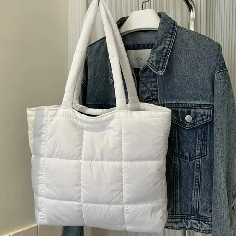 Svart vadderad shoppingväska med vit färg och pufferdesign.