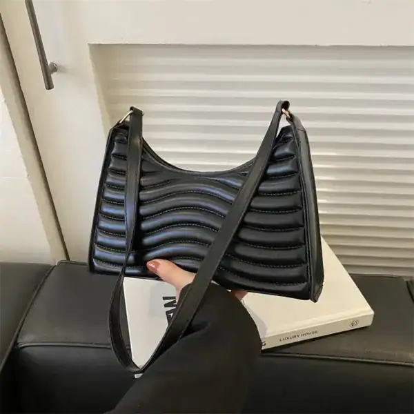 Svart vågig axelremsväska med strukturerad yta och elegant design.