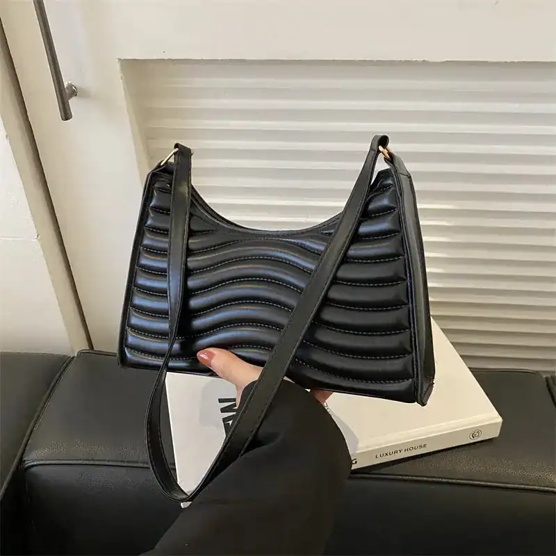 Svart vågig axelremsväska med strukturerad yta och elegant design.