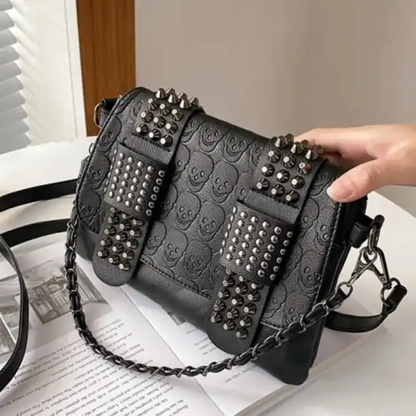 Svart axelväska med nitar och dödskalle-motiv, studded handväska.