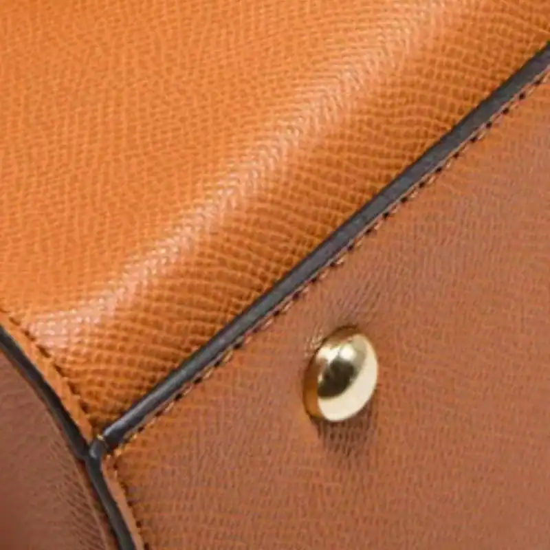 Svart väskset fyra delar, närbild på textil och metallknapp.