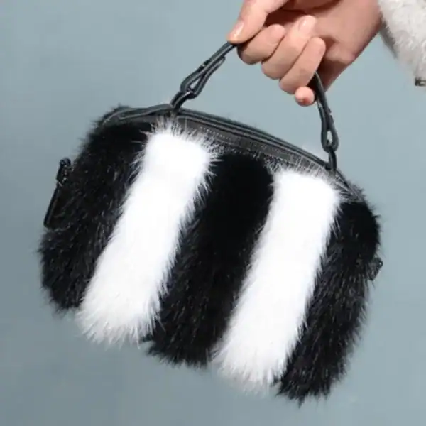 Svartvit pälsväska med randig pälsdesign och handtag.