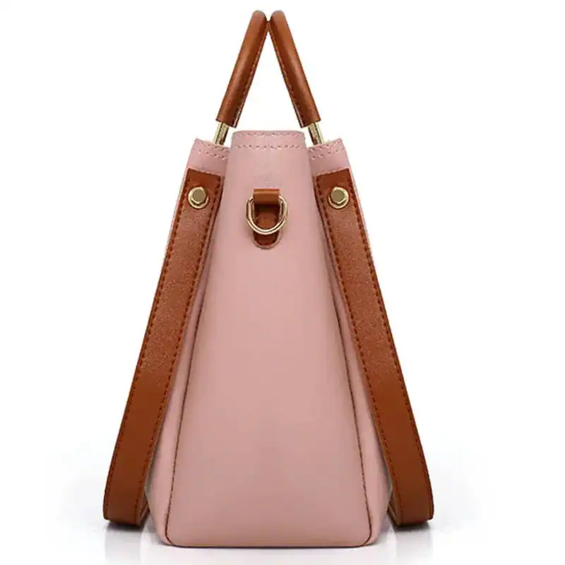 Trendig rosa handväska med bruna handtag och metallringar.