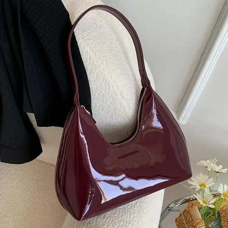 Vinröd lack hobo axelväska med glansig yta och hög handtag.