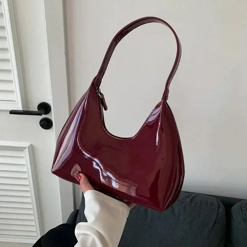 Vinröd lack hobo axelväska med glansig yta och enkel handtag.