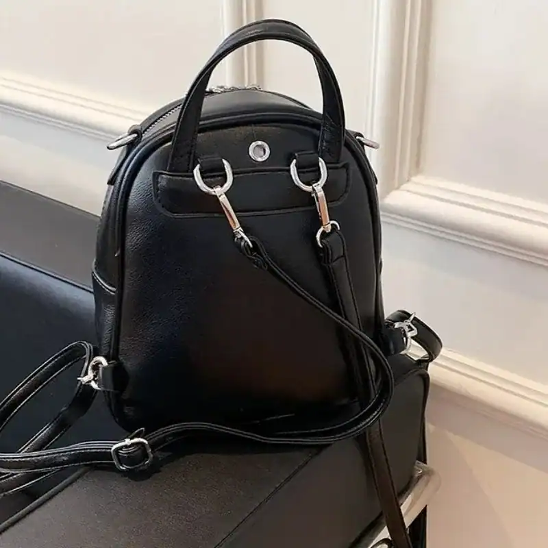 Vinröd liten ryggsäck, elegant design med handtag och axelrem.