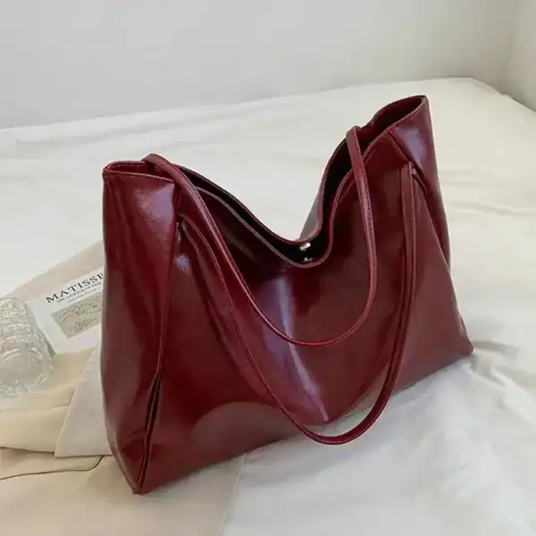 Vinröd shoppingväska med glansig yta och långt handtag, idealisk för vardag och shopping.