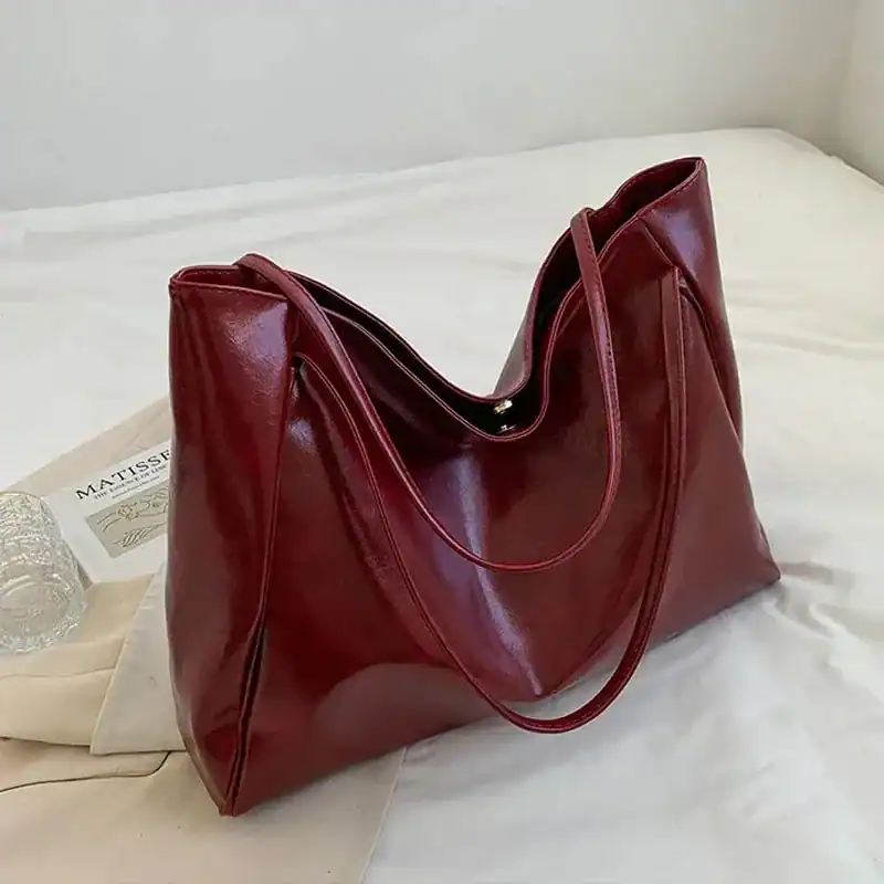 Vinröd shoppingväska med glansig yta och långt handtag, idealisk för vardag och shopping.