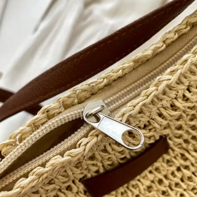 Virkad axelväska beige med metallisk dragkedja och brunt handtag.